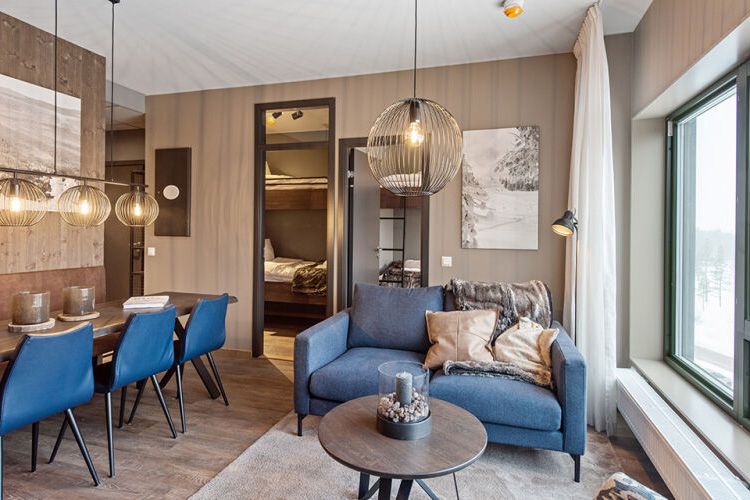 Living area of the 3 bedroom suite at the Ski Lodge Soltorget, with blue chairs and neutral brown décor