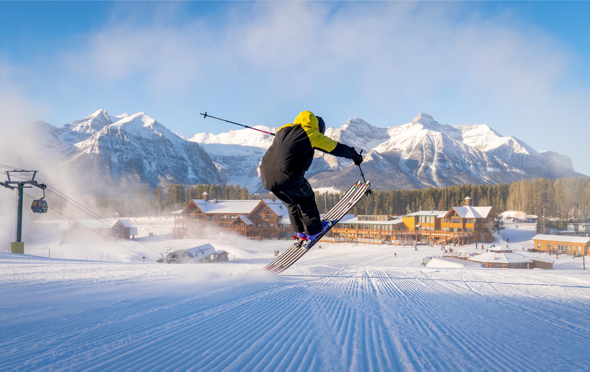 Skier jumping on groomed blues with the Rockies as a dramatic background Skier jumping on groomed blues with the Rockies as a dramatic background