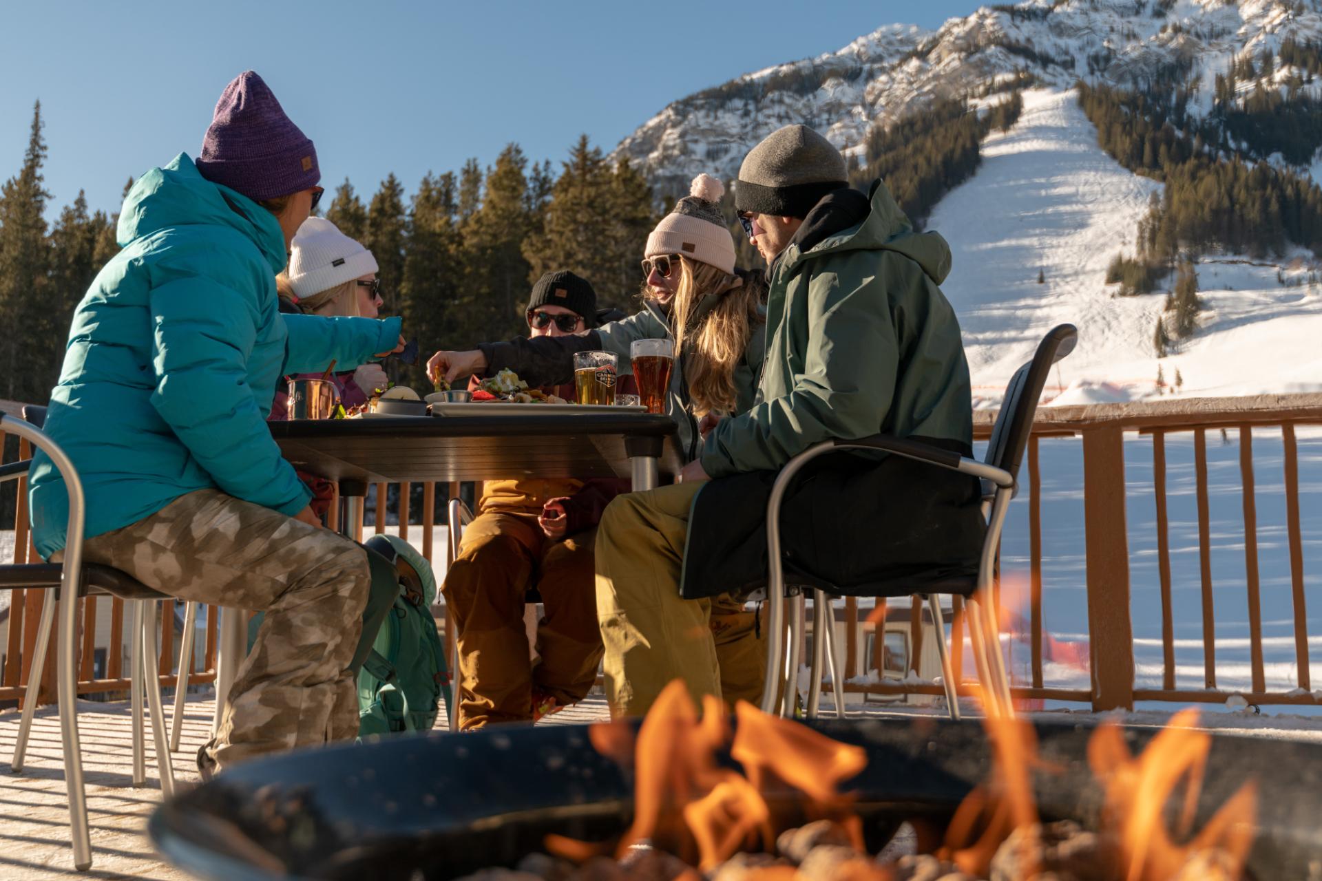 Four people enjoying food and drink at the base of Mt. Norquay resort Four people enjoying food and drink at the base of Mt. Norquay resort